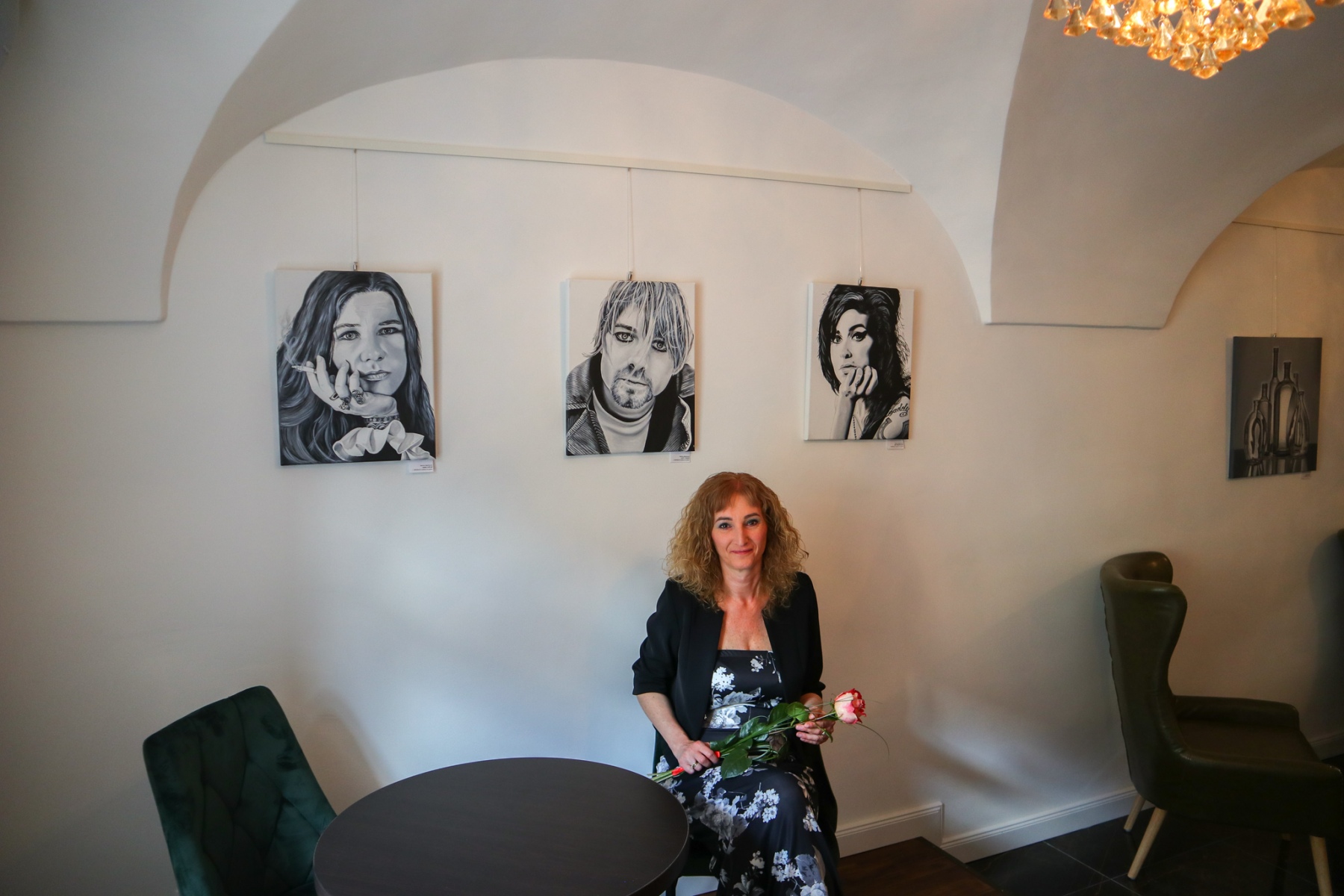 Martina Majcherová so svojimi obrazmi – portrétmi známych osobností, v kaviarni Bothár. (foto: KUNSTARTUM )