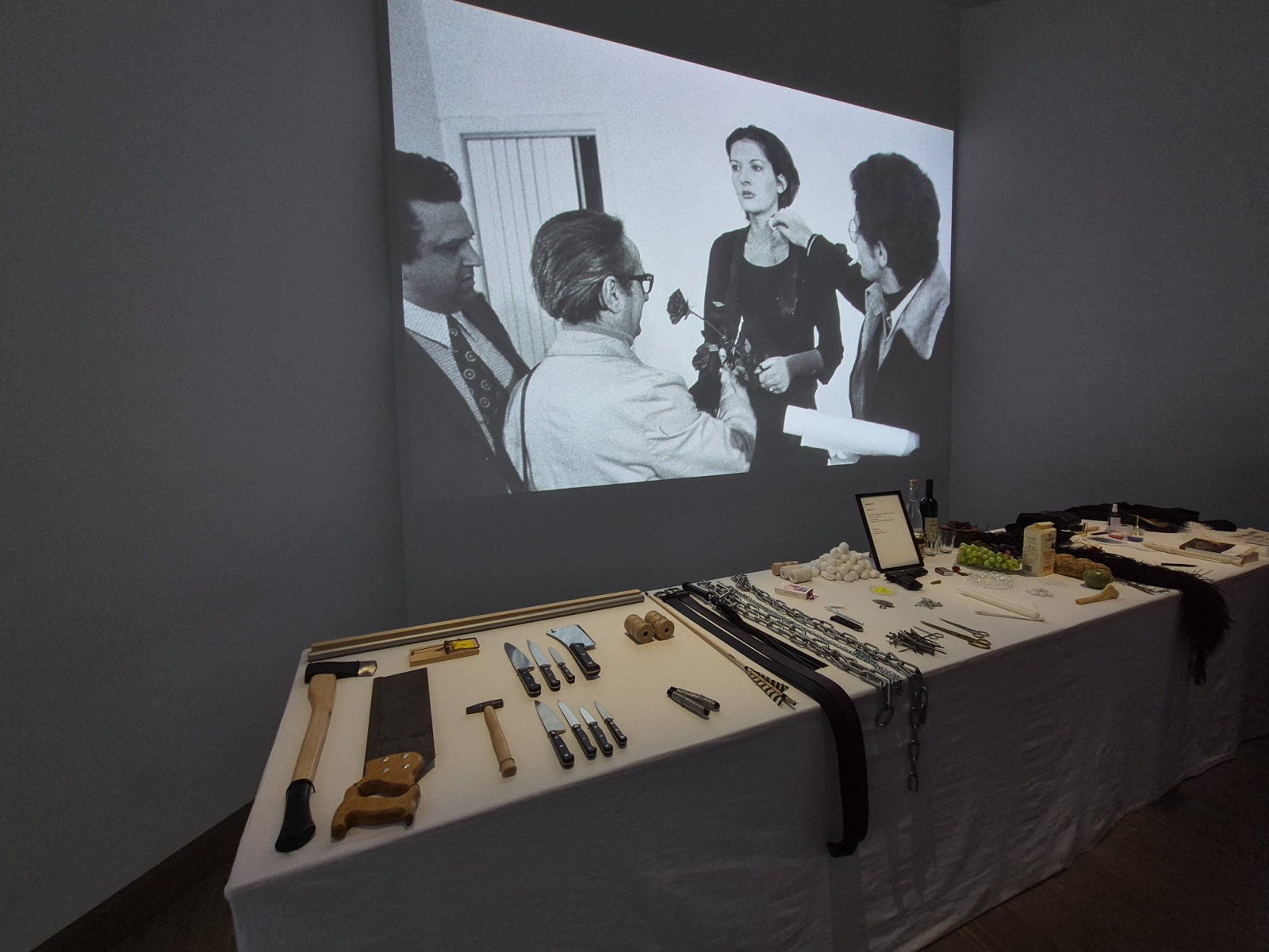 Marina Abramović: Rhythm 0, 1974, 6 hodinová performance – stôl, obrus a 72 objektov, Studio Morra, Neapol; projekcia bez zvuku + stôl s predmetmi použitými počas performance Rhythm 0. (foto: KUNSTARTUM)