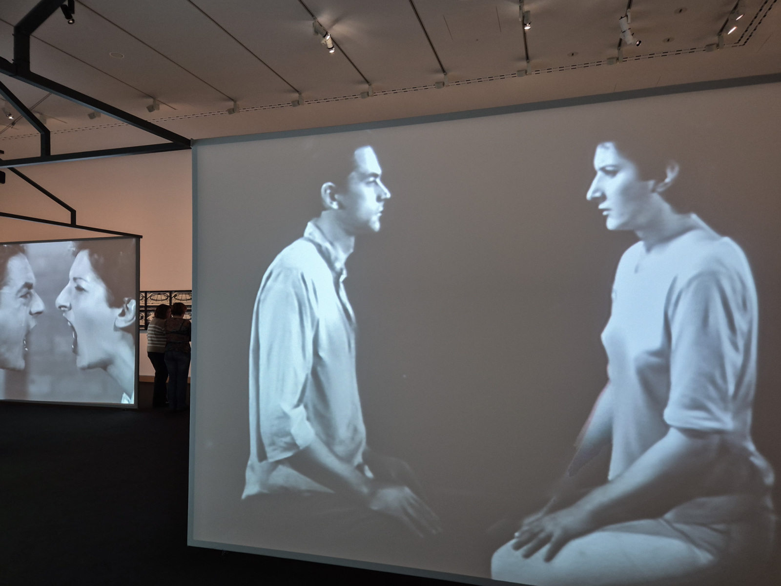Záznam z performance na plátne v popredí vpravo: Ulay/Marina Abramović: Light Dark, 1978, performance, 8 minút a 15 sekúnd, Amsterdam; 16mm čiernobiely film transformovaný na digitálne video so zvukom, 8 minút a 15 sekúnd.  Záznam z performance na plátne v pozadí vľavo: Ulay/Marina Abramović: AAA – AAA, 1978, 15 minútová performance, RTB Studio, Liège; čiernobiele video so zvukom, 12 minút a 58 sekúnd. (foto: KUNSTARTUM)