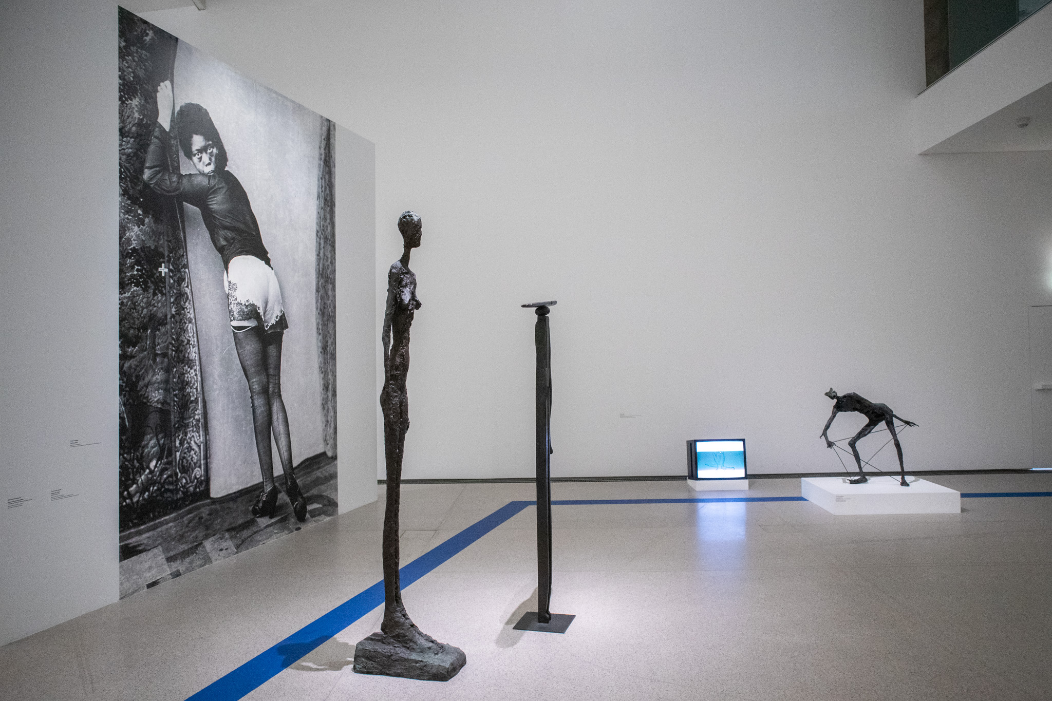Z výstavy Die Welt von morgen wird eine weitere Gegenwart gewesen sein, 2026, MUMOK, Viedeň. Pohľad do sekcie Fridy Orupabo. Diela zľava: Frida Orupabo: Turning, 2021, fotografická koláž; Alberto Giacometti: Femme debout III, 1962, bronz; Louise Bourgeois: Observer, 1947–1949, bronz; @nemiepeba: Bez názvu, 2017, video; Germaine Richier: Le Griffu, 1952, bronz.